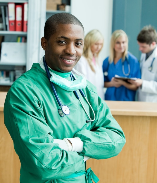 Portrait of a smiling surgeon with his team behind him