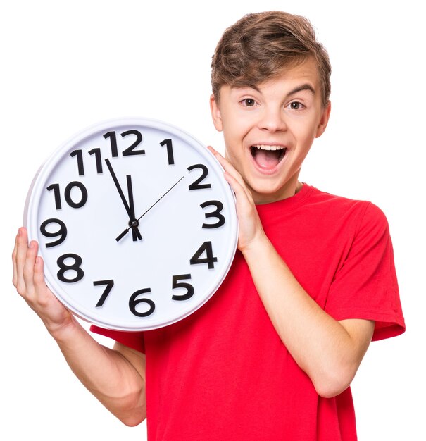 Portrait of smiling teen boy wearing red tshirt Teenager holding big clock Child back to school isolated on white Education and time concept