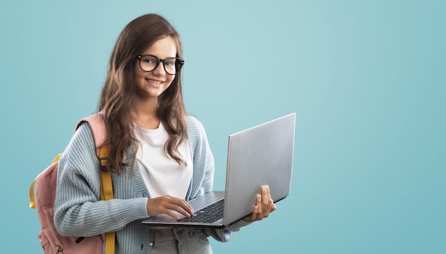 Portrait of smiling teen girl using a laptop computer, studying online