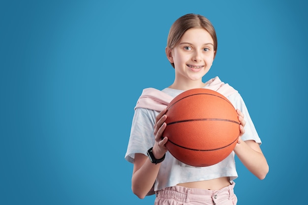 Portrait of smiling teenage girl holding basketball