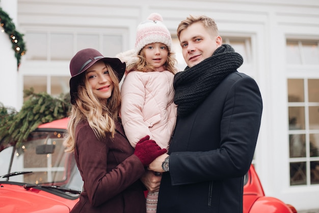 Портрет улыбающегося модные семьи создает открытый вместе в окружении снега и ели