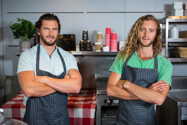 Portrait of smiling two male staff standing with arms crossed