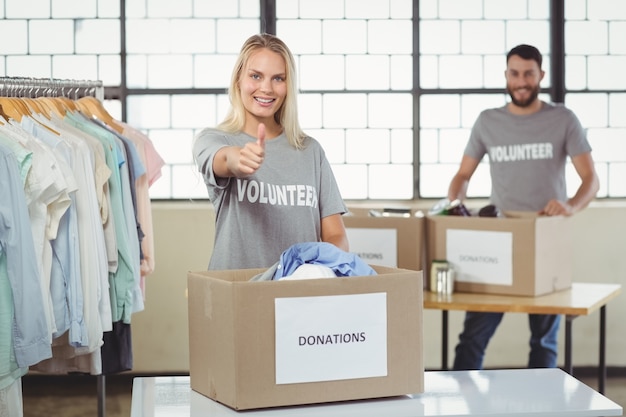 Portrait of smiling volunteer gesturing thumbs in office 