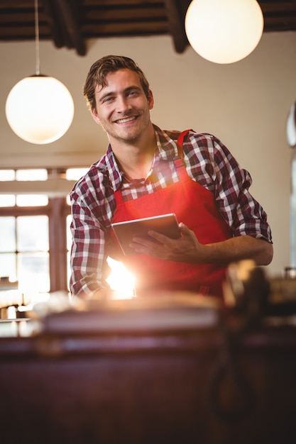 Portrait of smiling waiter holding digital tablet