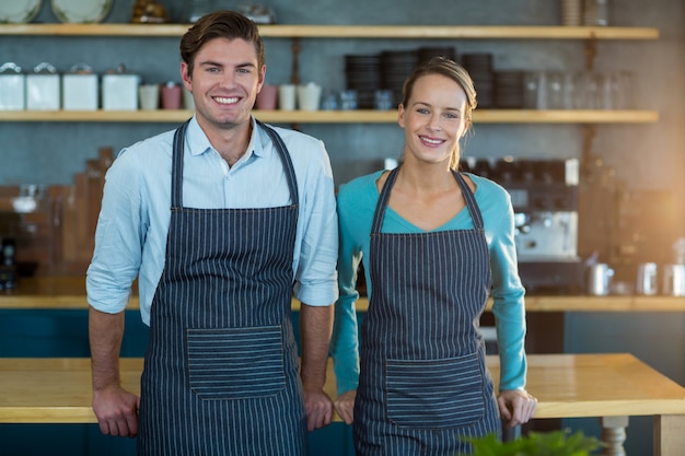 Портрет улыбающегося официанта и официантки, стоя у стойки