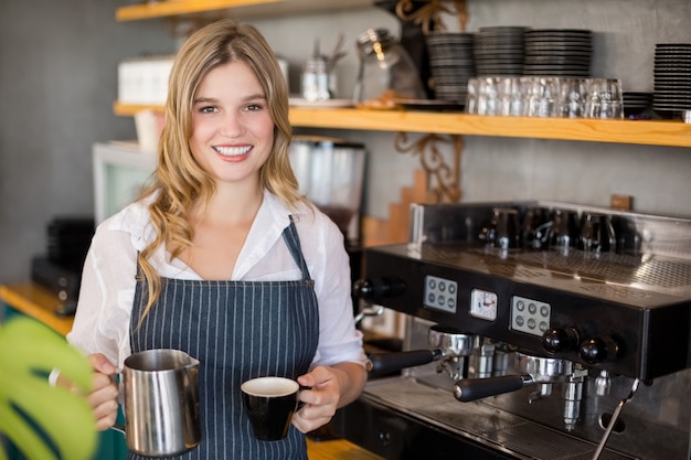 Ritratto della cameriera di bar sorridente che produce tazza di caffè