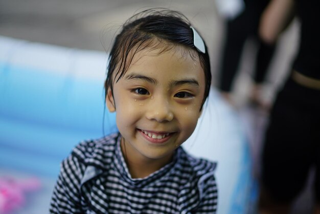 Photo portrait of smiling wet girl against swimming pool