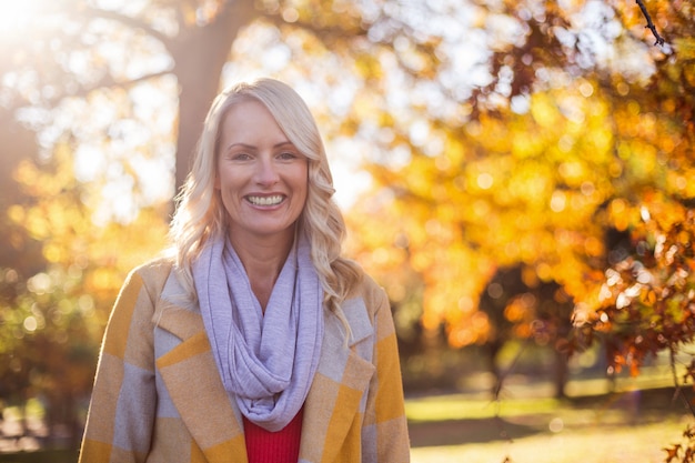 Portrait of smiling woman against trees at park