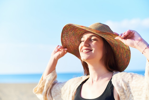 Portrait of smiling woman on beach wearing straw hat