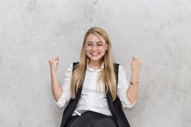 Photo portrait of smiling woman clenching fists against wall