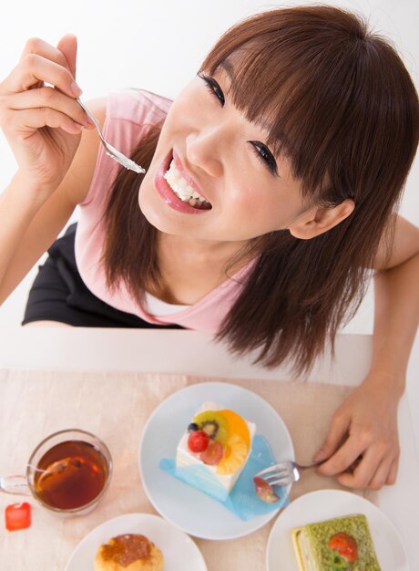 테이블 위 에 있는 접시 에 케이크 를 먹고 있는 미소 짓는 여자 의 초상화