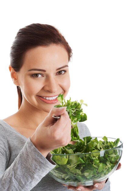 Foto ritratto di una donna sorridente che mangia verdure su uno sfondo bianco