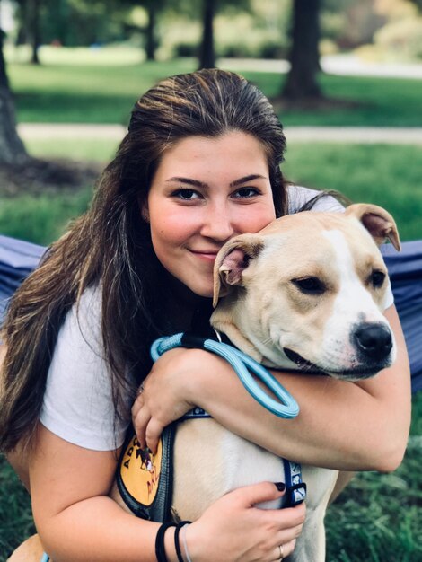 Foto ritratto di una donna sorridente che abbraccia un cane all'aperto