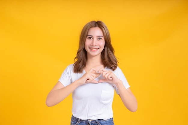 Portrait of smiling woman gesturing against yellow background