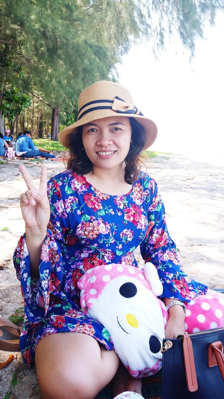 Photo portrait of smiling woman gesturing while sitting at beach