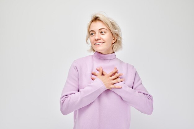 白い背景に隔離された感謝や喜びを表す胸の上に笑顔の女性の手の肖像画