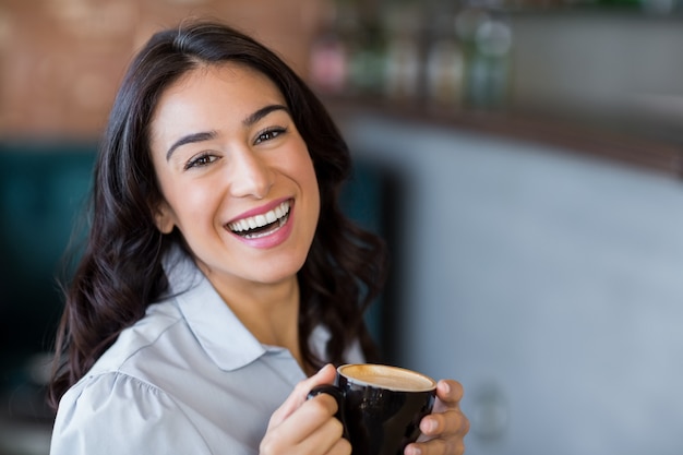 一杯のコーヒーを持つ笑顔の女性の肖像画