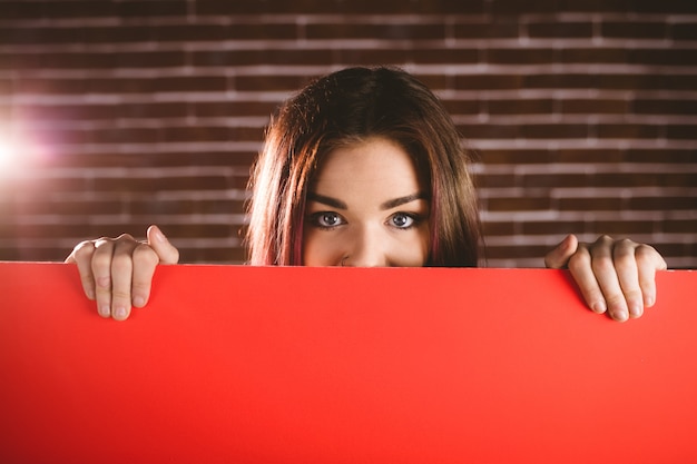 Portrait of smiling woman hiding face from blank placard