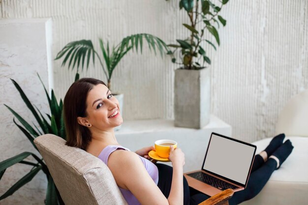 Photo portrait of smiling woman holding coffee cup sitting at home