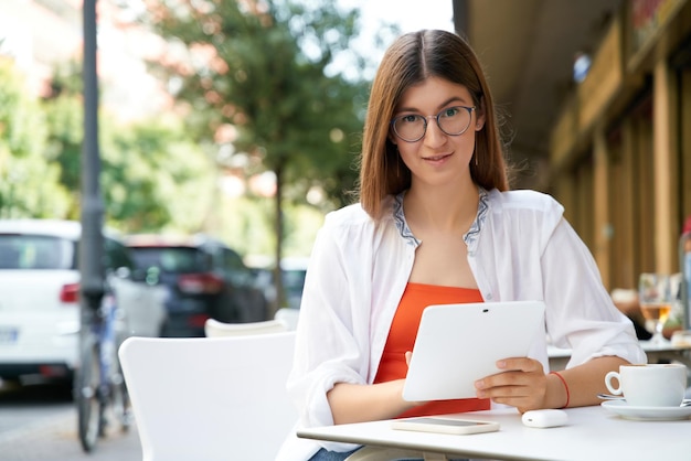 Portrait of smiling woman holding credit card, using mobile phone shopping online sitting cafe