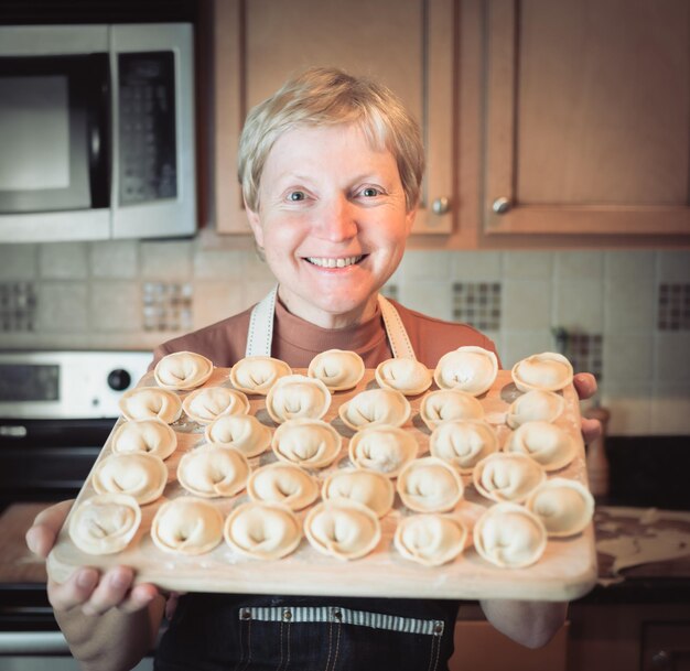 Foto ritratto di una donna sorridente che tiene la pasta in cucina