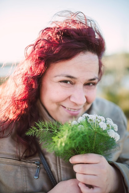 Photo portrait of smiling woman holding flowers