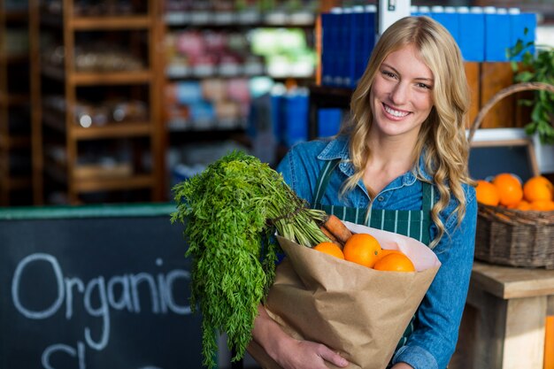 Photo portrait of smiling woman holding a grocery bag in organic section