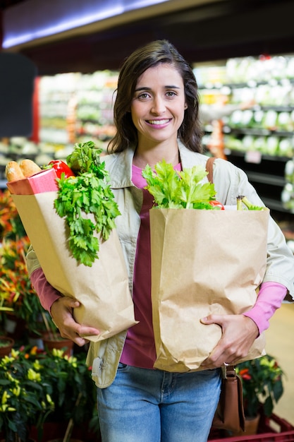 Портрет улыбается женщина, держащая продуктовый мешок в органическом разделе