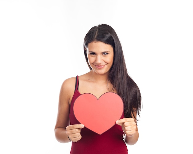 Portrait of smiling woman holding heart shape against white background
