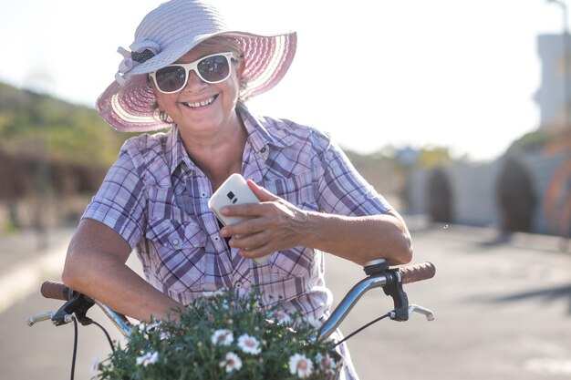 Portrait of smiling woman holding mobile phone on bicycle