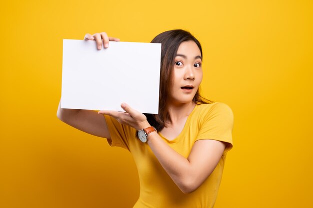 Portrait of smiling woman holding placard against yellow background