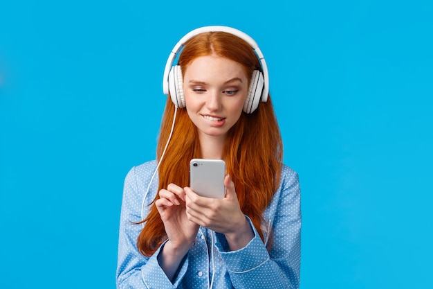 青い背景にスマートフォンを握っている笑顔の女性の肖像画
