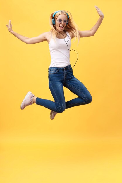 Foto ritratto di una donna sorridente che salta su uno sfondo giallo
