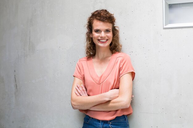 Portrait of smiling woman leaning against concrete wall