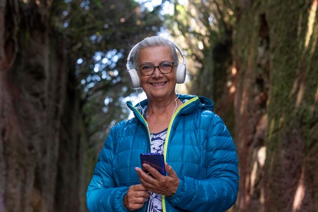 Photo portrait of smiling woman listening music standing against trees