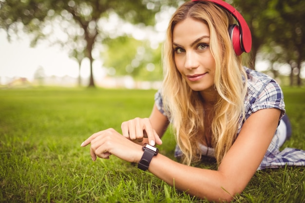 Portrait of smiling woman listening to music and touching wristwatch 
