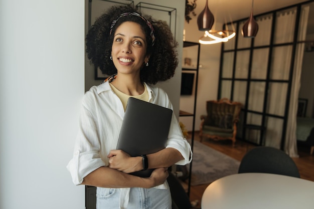 Photo portrait of smiling woman looking at camera hold laptop