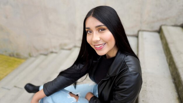 Portrait of smiling woman looking at camera sitting on a concrete staircase