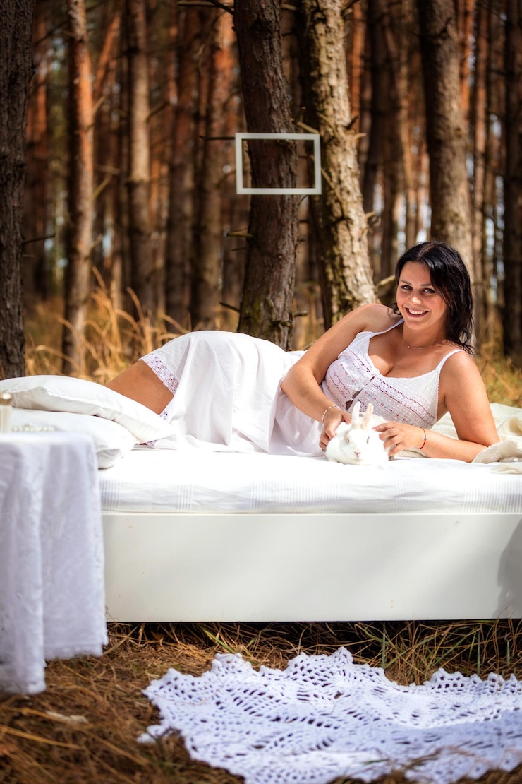Photo portrait smiling woman lying on bed with rabbit in forest