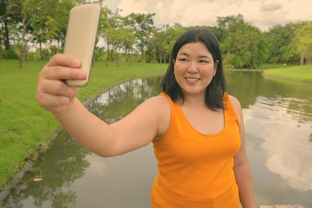 Photo portrait of smiling woman photographing while standing on water