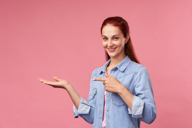 Portrait of a smiling woman pointing to the side