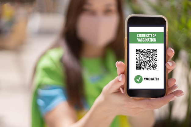 Portrait smiling woman posing with vaccine certificate on smartphone screen coronavirus prevention