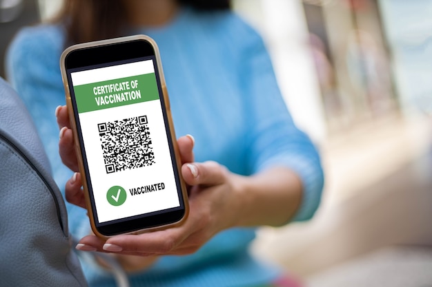 Portrait smiling woman posing with vaccine certificate on smartphone screen coronavirus prevention