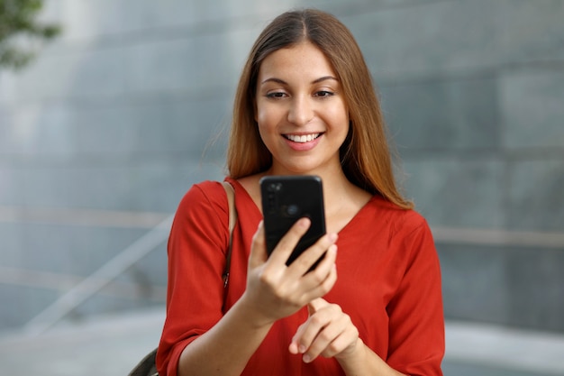 Portrait of a smiling woman sending text message from her phone