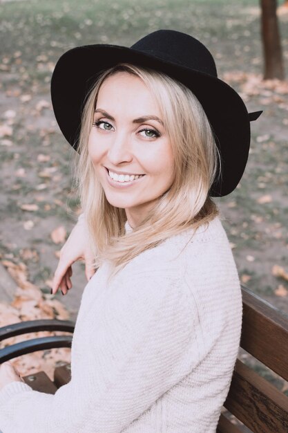 Portrait of smiling woman sitting on bench at park