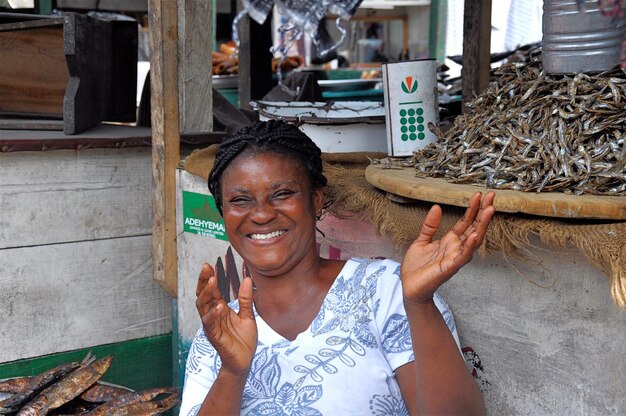 Portrait of smiling woman sitting by market stall