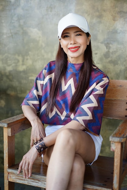 Photo portrait of smiling woman sitting on chair against wall