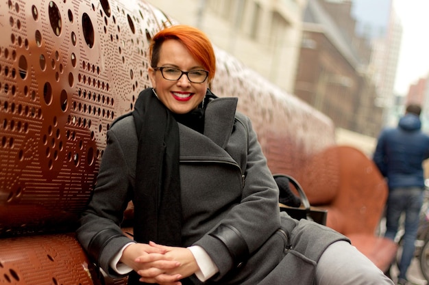 Photo portrait of smiling woman sitting in city