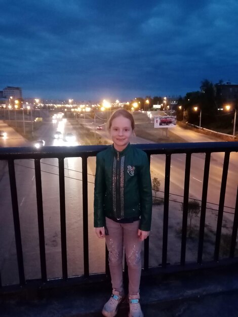 Portrait of smiling woman standing against illuminated city at night