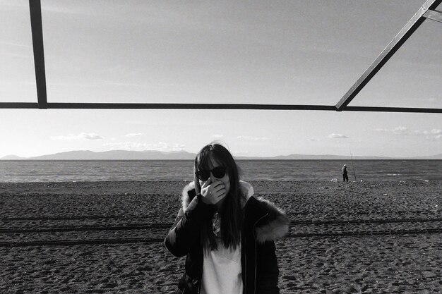 Photo portrait of smiling woman standing at beach against sky